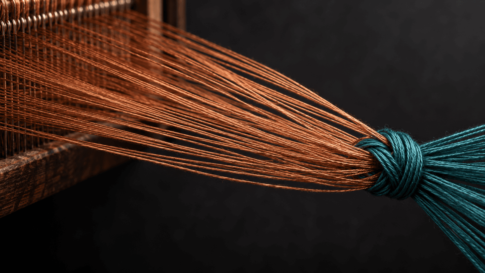 Copper threads gathered into a teal knot on a loom